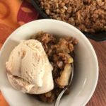 scoop of ice cream on apple crisp in a white bowl