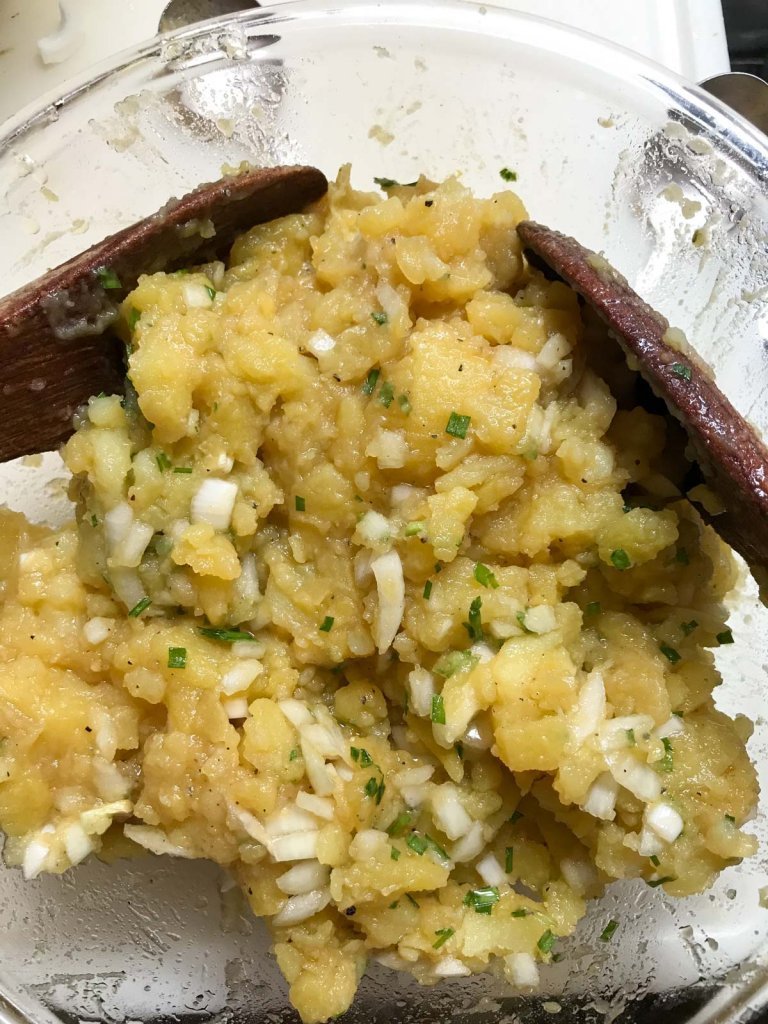 Potato salad in a glass bowls with wood tongs