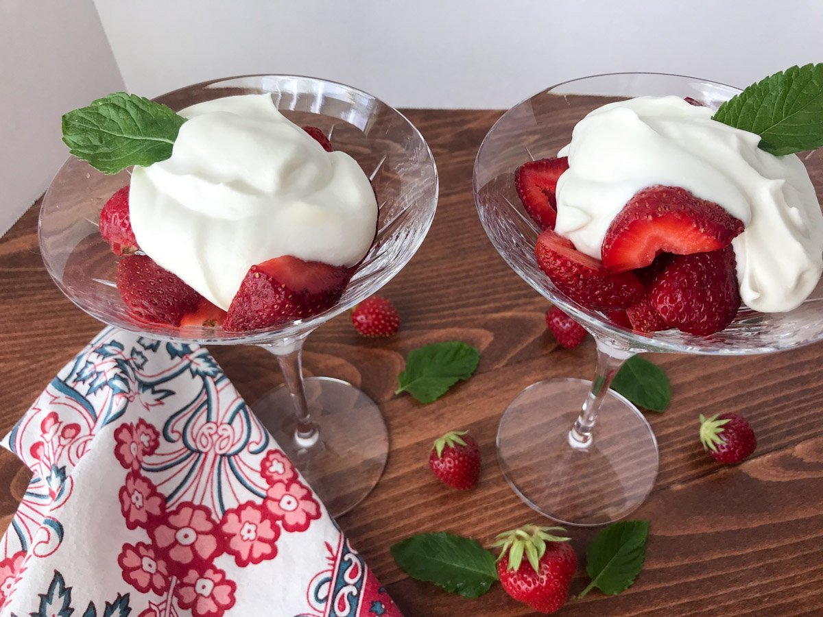 Side view of two martini glasses filled with strawberries and cream